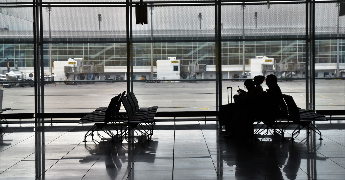 a group of people sitting in an airport waiting area, with luggage nearby.