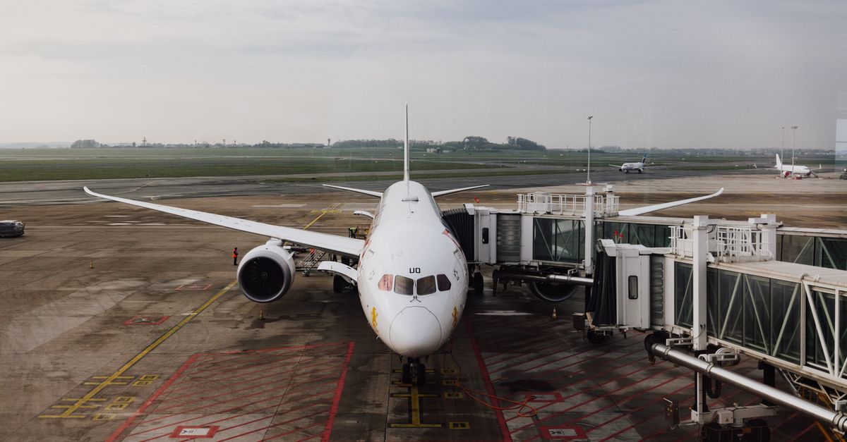 A passenger plane parked at a terminal, with a jetway attached.