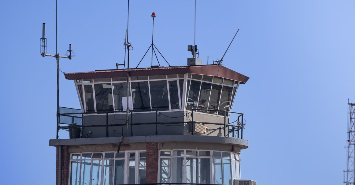 A modern airport control tower against a clear blue sky, showcasing aerial communication infrastructure.