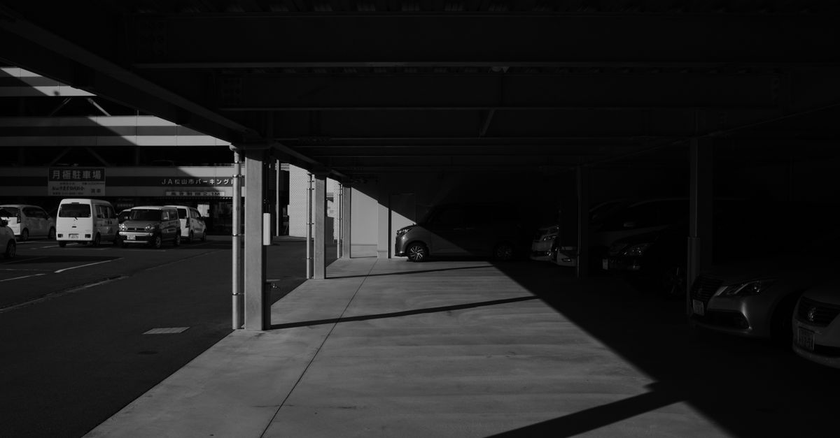 A covered walkway in a parking lot, with a car parked in the distance.