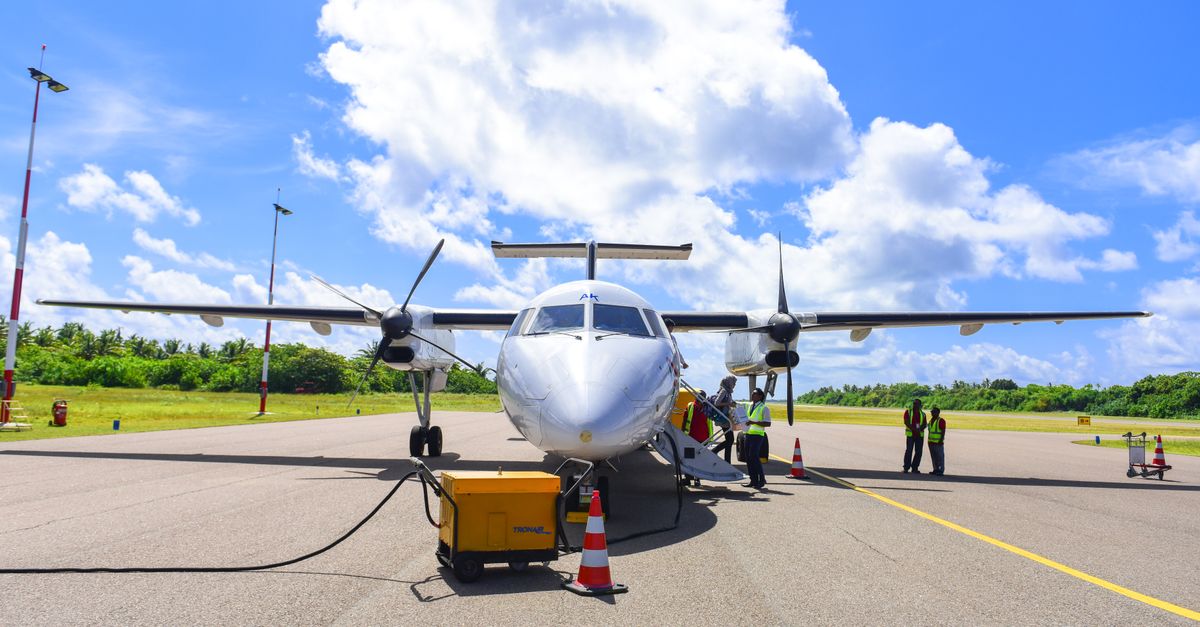 A small white plane on a tarmac, with a staircase leading up to the cockpit.