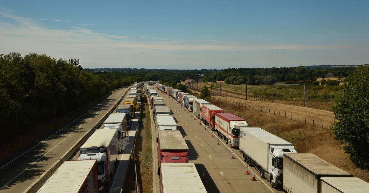 Aerial view of heavy traffic with trucks on an English highway under blue skies.