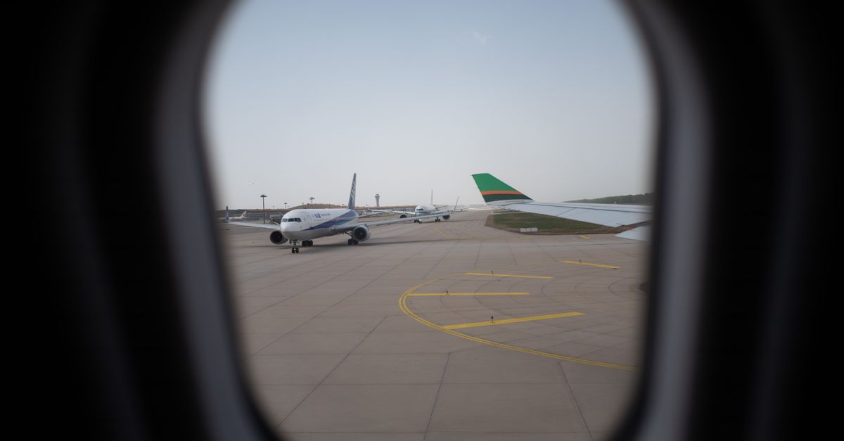 An airport runway viewed through the window of an airplane.