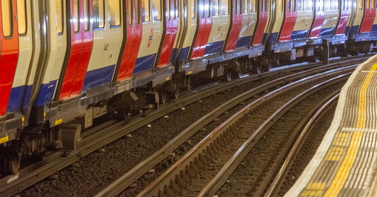 Vibrant red and blue subway trains navigate curved tracks at an underground station platform.