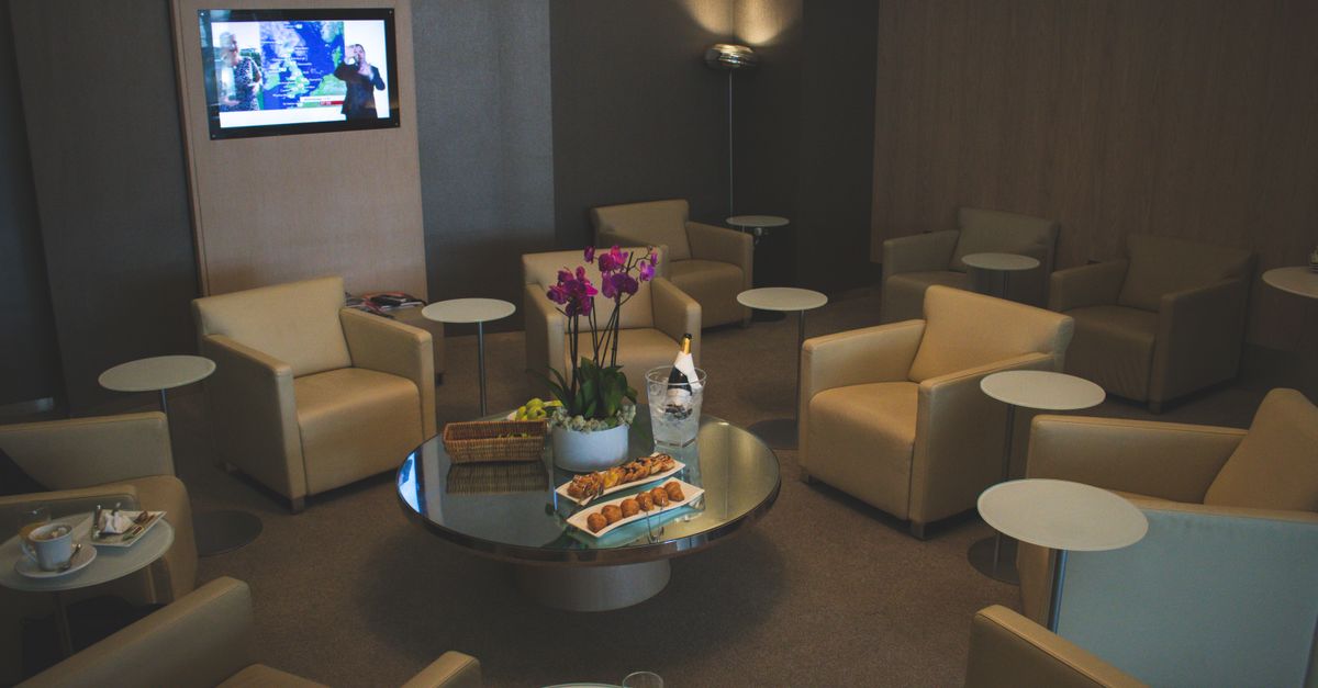 Calm airport lounge seating area with sofas and refreshments on a low table.