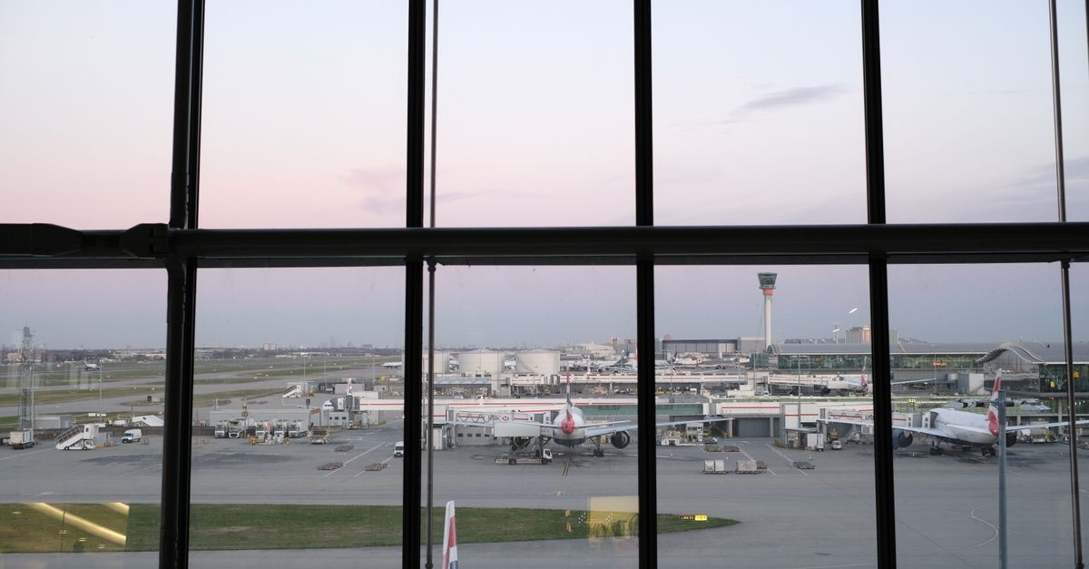 View through terminal windows of British Airways aircraft on the apron with a control tower behind.