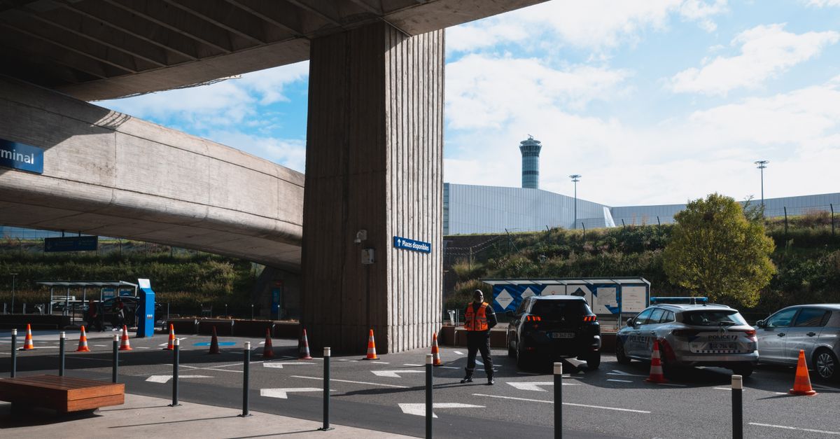 A bustling airport entrance with vehicles and people in Roissy, France.