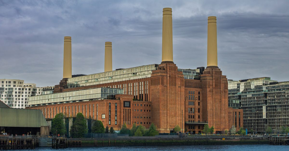 Iconic Battersea Power Station by the Thames in London under a cloudy sky.