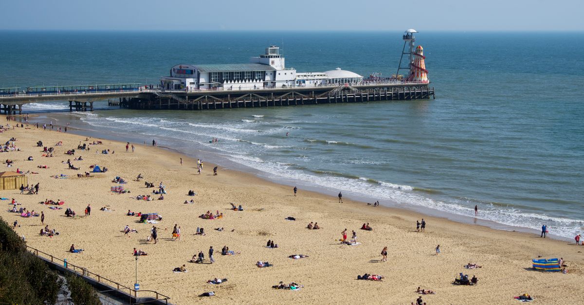 A vibrant summer day at Bournemouth Beach with the iconic pier in the background.