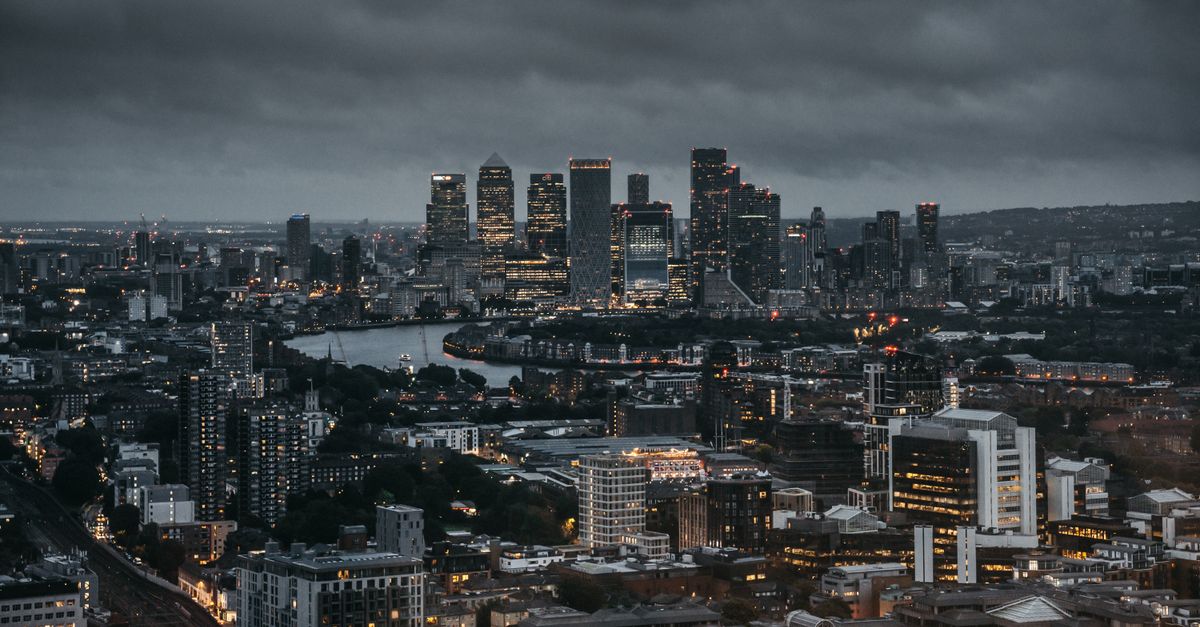 Stunning aerial view of a city's illuminated skyline at night, showcasing skyscrapers and a winding river.