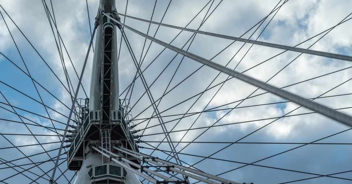 Close-up view of the London Eye's intricate steel structure against a cloudy sky.