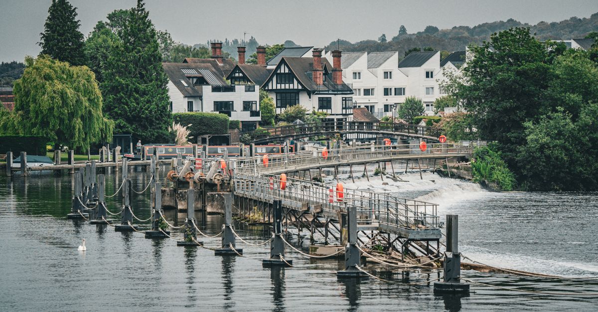 Picturesque view of traditional houses and a weir on the Thames River in London, UK.