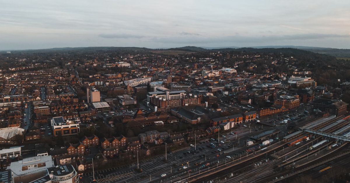 Aerial shot of Guildford, UK, showcasing urban cityscape and train tracks at dusk.