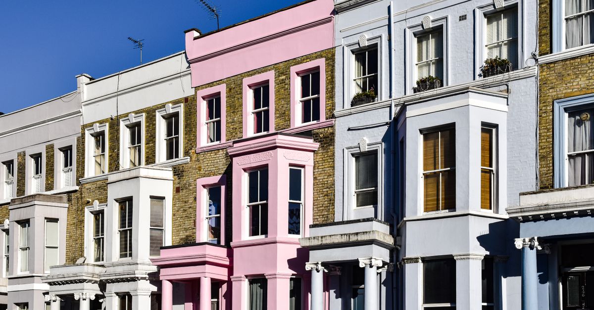 Vibrant multi-colored Victorian row houses in Notting Hill, bathed in sunlight under a clear blue sky.