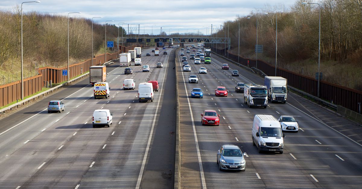 Aerial view of a UK motorway with cars, vans and lorries in daytime traffic.