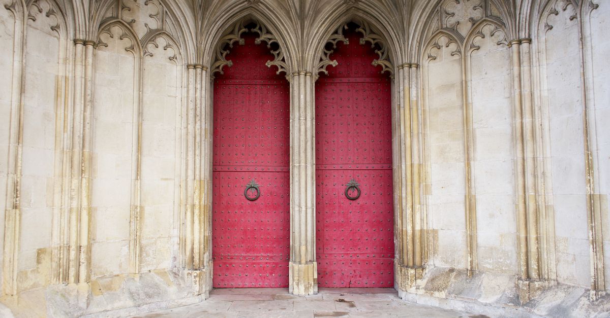 Explore the gothic architecture of Winchester Cathedral's red doors and detailed arches in England.