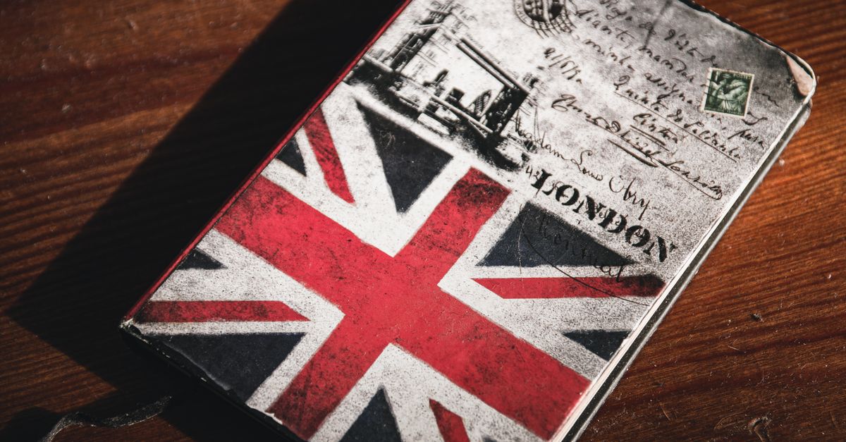 A close-up of a vintage notebook featuring the Union Jack and London postcard imagery on a wooden table.